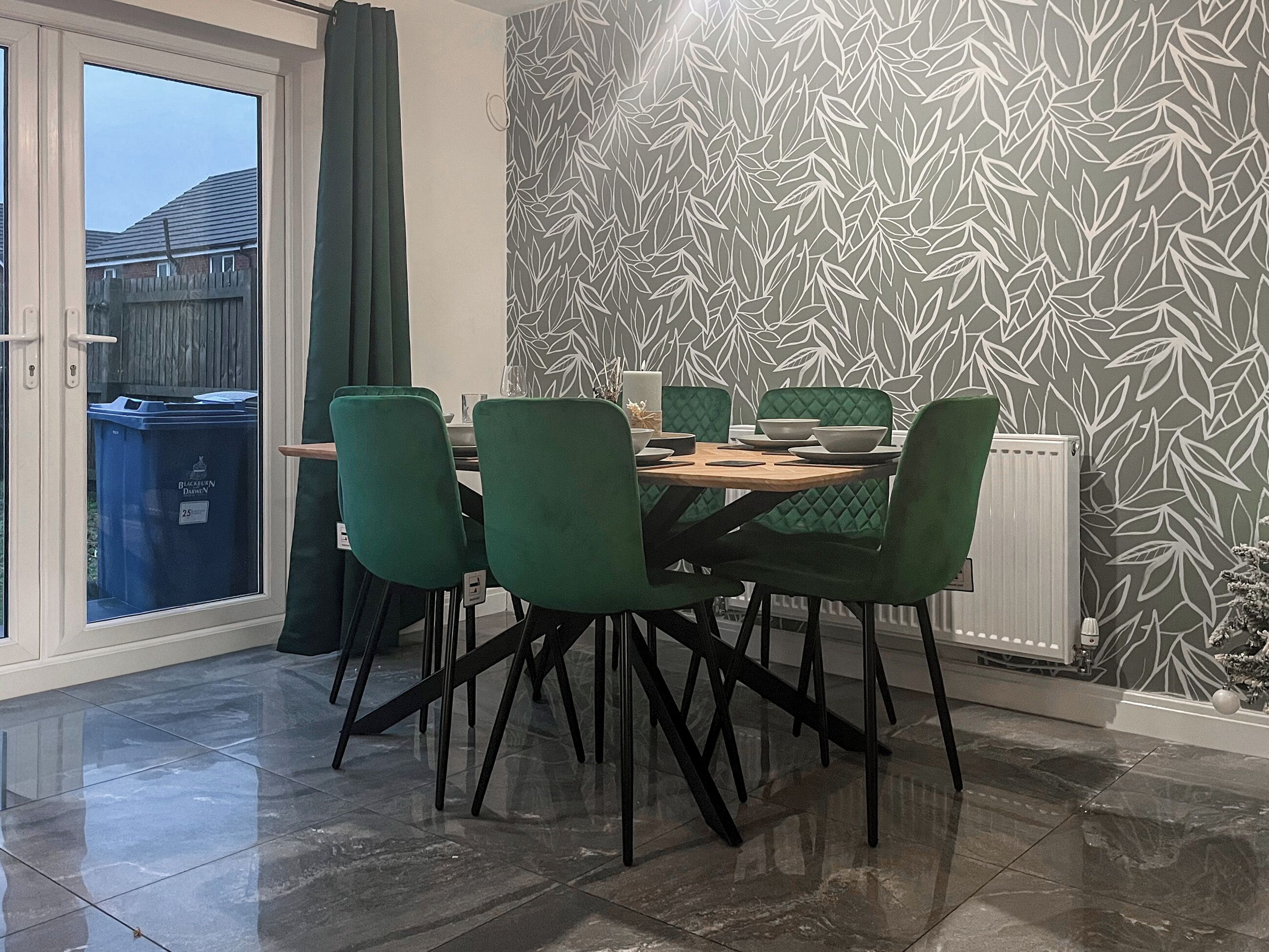 A dining area with a table, chairs, and a patterned wall.