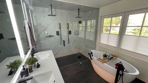 A modern bathroom with a glass-enclosed shower, a freestanding bathtub, and a white vanity with a mirror. - Summerland Lakeview Vineyard with Pool (Summerland)