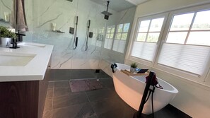 A modern bathroom with a large bathtub, a separate shower area, and a vanity with a mirror. - Summerland Lakeview Vineyard with Pool (Summerland)