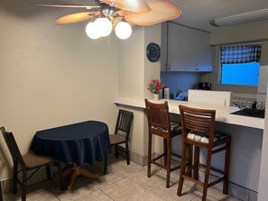 A compact kitchen with a dining area, including a round table, two chairs, and a ceiling fan. - Waikiki condo/2 bedroom/FREE parking /4beds (Honolulu)