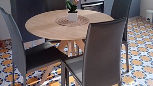 A compact kitchen with modern appliances, a round dining table, and chairs. - BGM Apartment Milan Rho Fiera—trains every 15 minutes to Milan (Cesate)