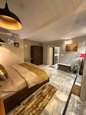 A bedroom with a bed, a wooden wardrobe, a bench, a potted plant, and a painting on the wall. - Mountain Glory (Mussoorie)