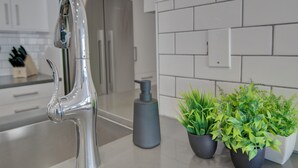 Een moderne keuken met een roestvrijstalen kraan, een zeepdispenser en potplanten op het aanrecht.