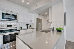 A modern kitchen with stainless steel appliances, white cabinetry, and a large island.