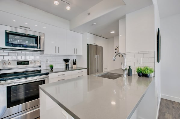 Una cocina moderna con electrodomésticos de acero inoxidable, armarios blancos y una isla grande.