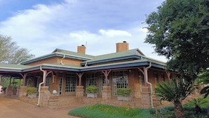 A brick building with a green roof, large windows, and a covered porch area.