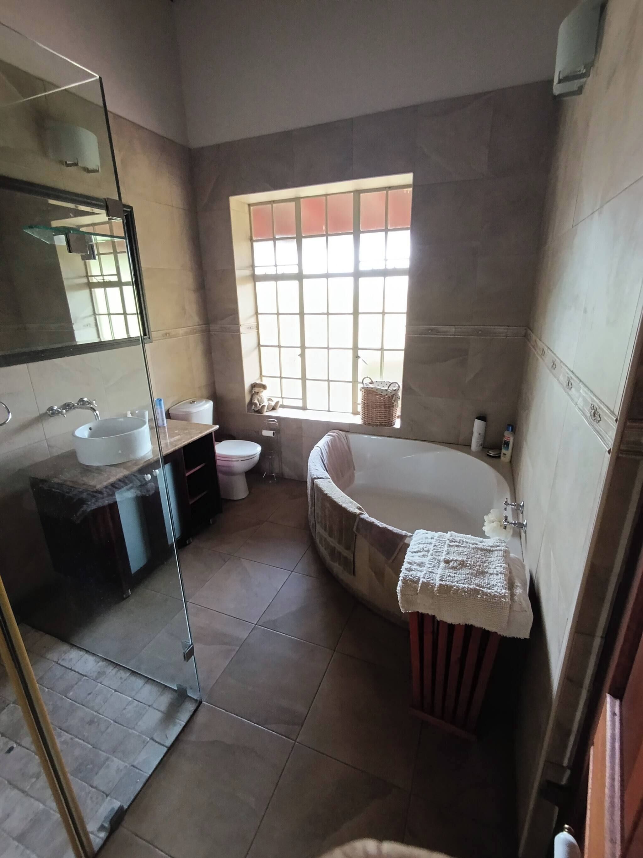 Une salle de bain avec une baignoire, des toilettes, un lavabo, une fenêtre et un miroir.