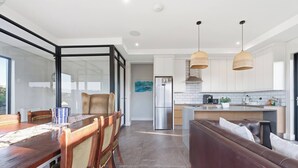 Una cucina moderna con zona pranzo, divano e vista panoramica tramite una porta in vetro.