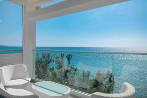 A balcony with a view of the sea, white wicker furniture, and a glass railing. - Luxury Beach Front Flat Kyma 3 (Germasogeia)