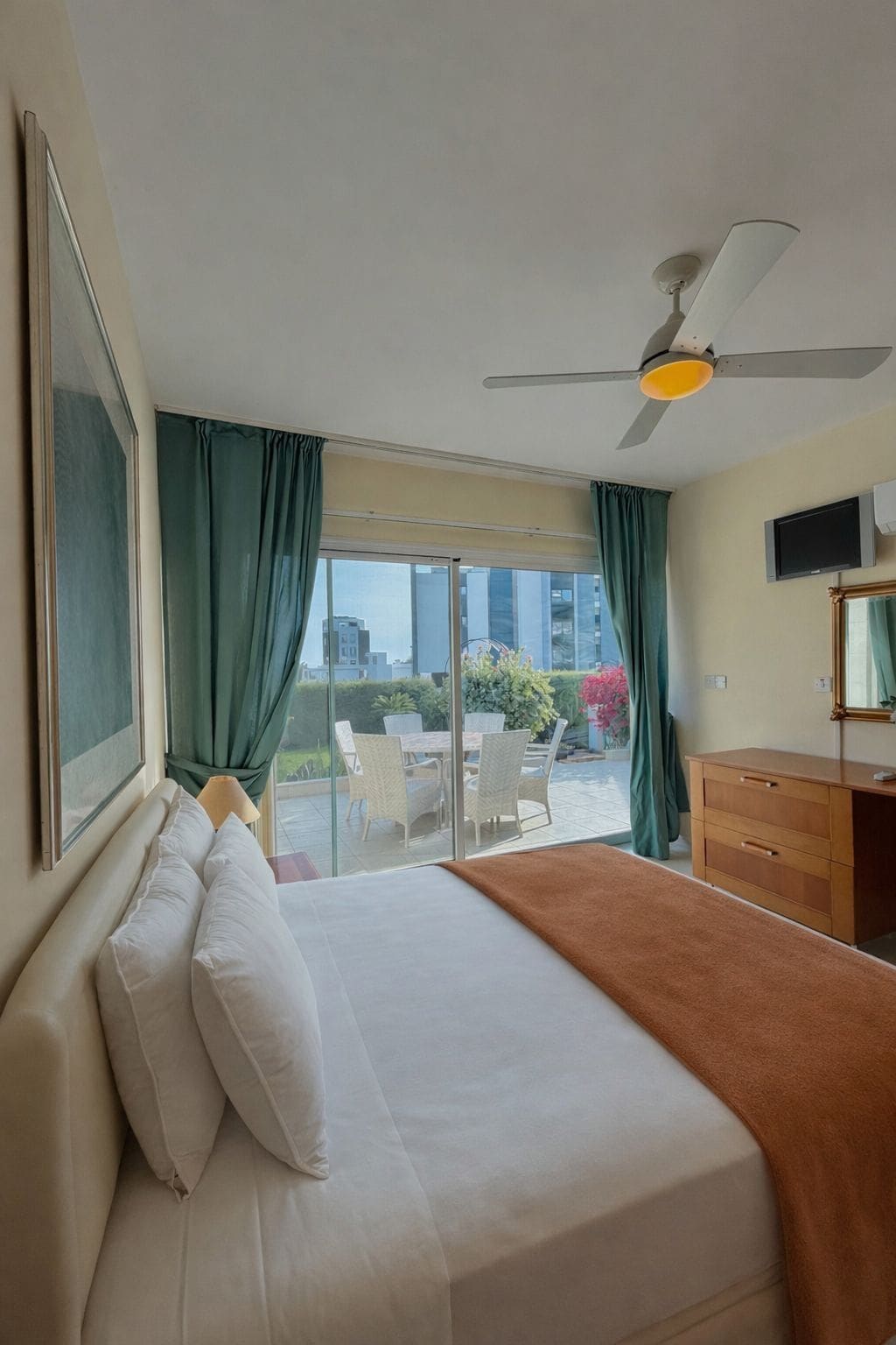 A hotel room with a bed, a desk, a television, and a view of the outdoors.