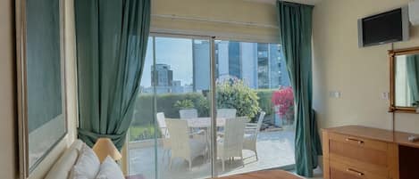 A hotel room with a bed, a desk, a television, and a view of the outdoors.