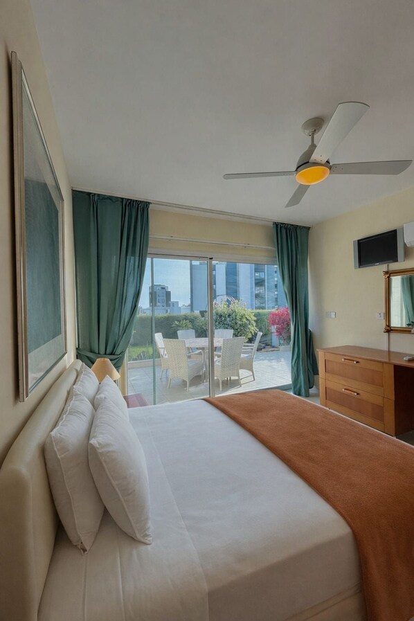 Ein Hotelzimmer mit Bett, Schreibtisch, Fernseher und Blick ins Freie.