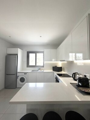 A modern kitchen with a central island, built-in appliances, and ample counter space. - Seaside Comfort Stay Flat Constantinos 113 (Pafos)