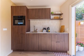 Eine kompakte Küche mit Holzausstattung, einem eingebauten Backofen und einer Kaffeemaschine auf der Arbeitsfläche.