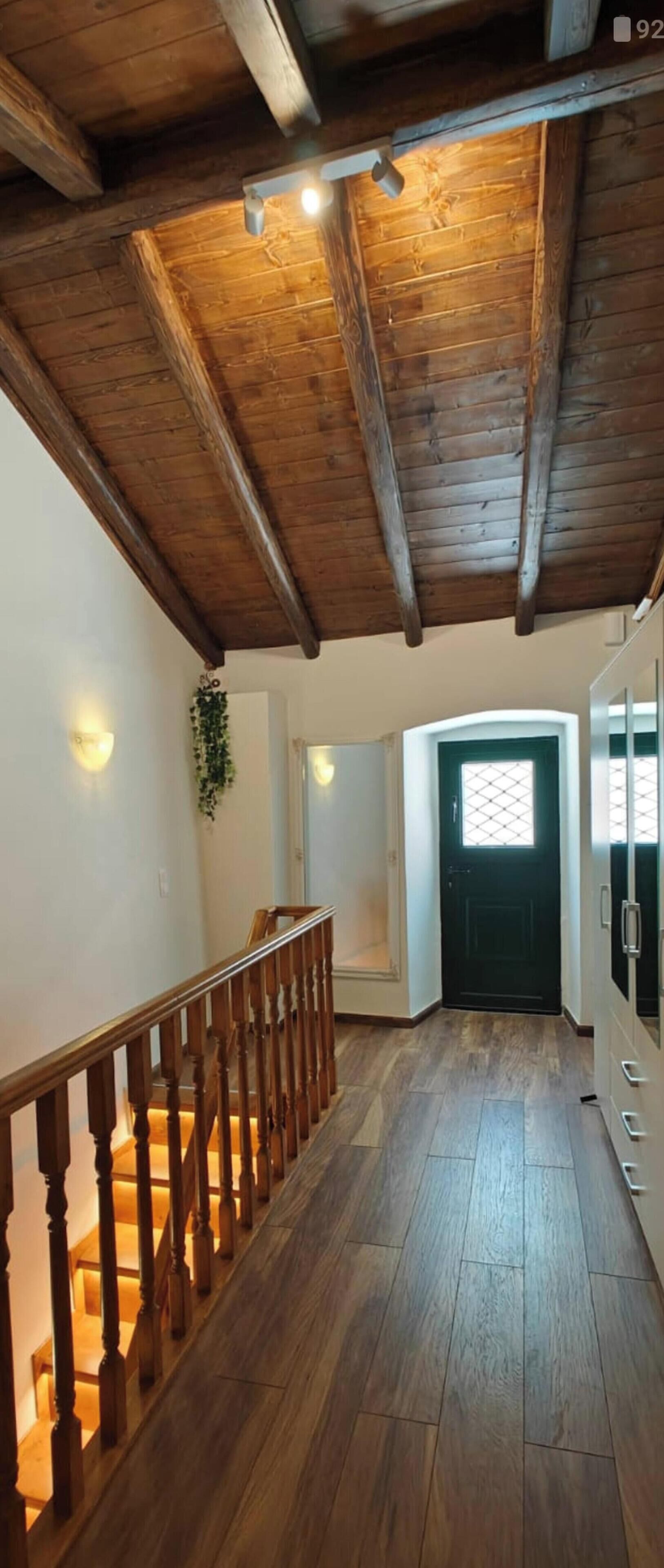 A wooden staircase leading to a room with a black door and a window with a grid pattern.