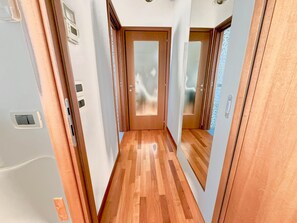 A narrow hallway with wooden flooring, a door at the end, and a light switch on the wall. - 2 steps from the sea with terrace, double air conditioner - sleeps 4 (Pescara)