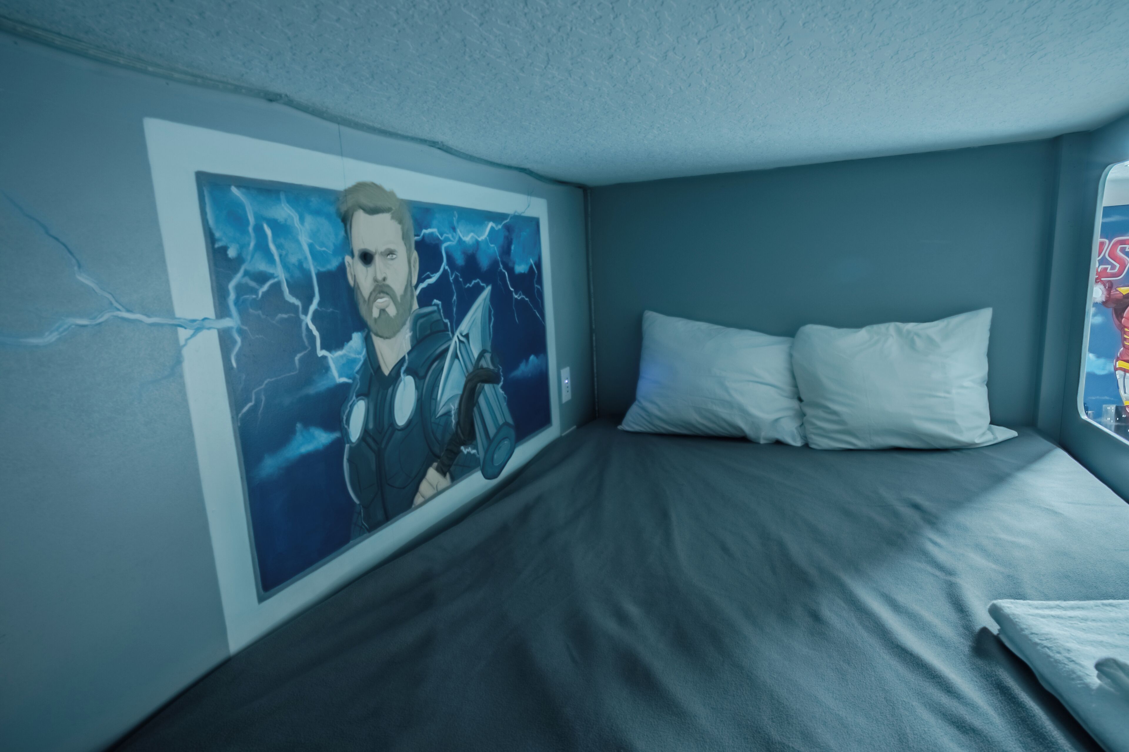 Une chambre à coucher avec un lit, une peinture murale et une fenêtre.