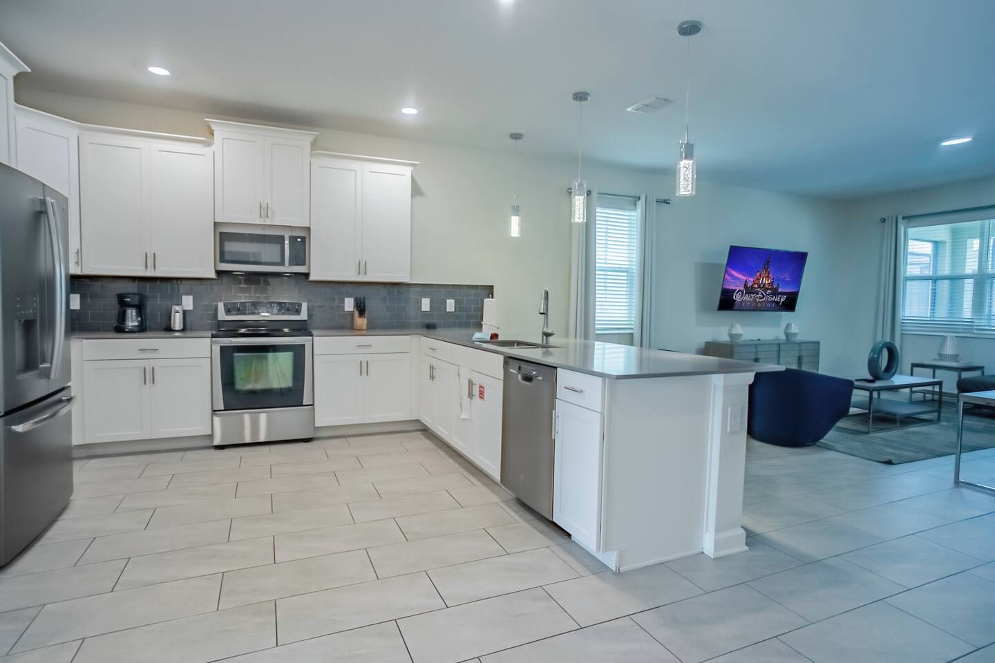 A modern kitchen with white cabinetry, stainless steel appliances, and a large island.