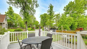 A deck with a round table and chairs, surrounded by white railings, overlooking a backyard with trees and a house. - Fenced Yard! Family Home, 14 Mi to DC Sites (Lanham)