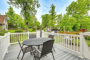 A deck with a round table and chairs, surrounded by white railings, overlooking a backyard with trees and a house. - Fenced Yard! Family Home, 14 Mi to DC Sites (Lanham)