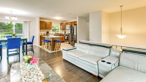 A modern living room with a sofa, a dining area with chairs, a kitchen with appliances, and a view of the outdoors. - Fenced Yard! Family Home, 14 Mi to DC Sites (Lanham)