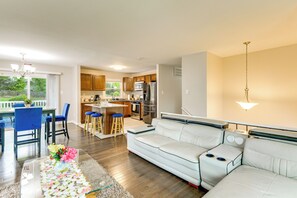 A modern living room with a sofa, a dining area with chairs, a kitchen with appliances, and a view of the outdoors. - Fenced Yard! Family Home, 14 Mi to DC Sites (Lanham)