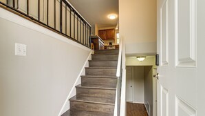 A staircase leading to a kitchen area with wooden steps and a white door at the bottom. - Fenced Yard! Family Home, 14 Mi to DC Sites (Lanham)