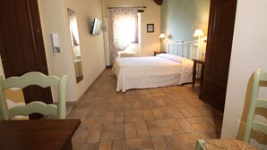 Une chambre à coucher avec un lit, une chaise, une table, une fenêtre avec des rideaux et une porte.