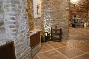 Ein Zimmer mit Stehwänden, einem Kamin, einem Holzstuhl und einem Tisch mit einer Lampe.