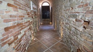 Passadís estret amb parets de maó i terra de rajola, que condueix a una porta.