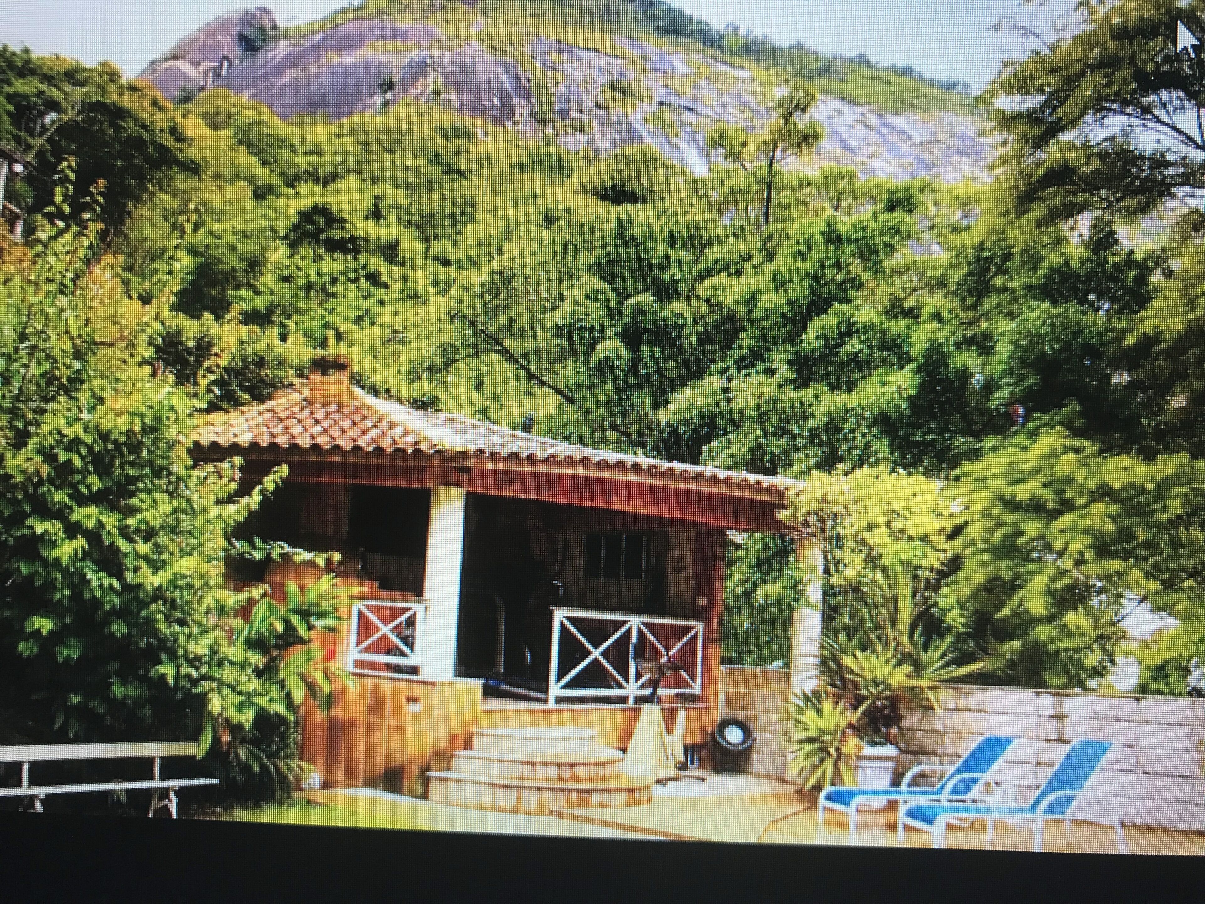A small house with a tiled roof, a porch, and a bench.