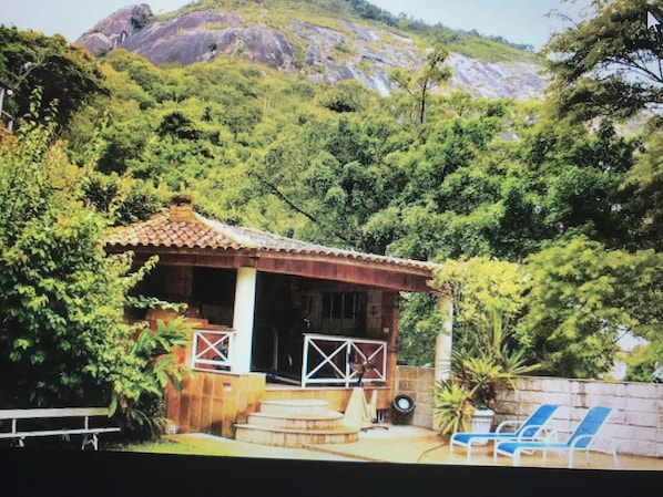 A small house with a tiled roof, a porch, and a bench.