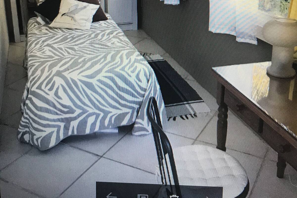 A bedroom with a bed, a bedside table, a chair, curtains, and a window.