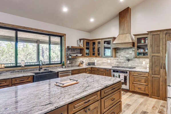 A modern kitchen with wooden cabinets, a large island, and a built-in oven. - Spacious Family Gem w/ Patio, 3 Mi to Rainbow Lake (Lakeside)