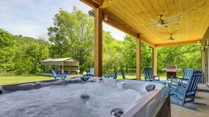 A hot tub with chairs and a ceiling fan in a covered outdoor area. - Smoky Mountain Riverfront Barndominium (Kodak)