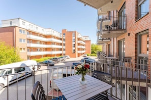 A balcony with a table, chairs, and a vase of flowers.