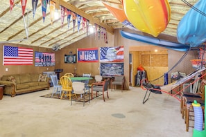 A room with a high ceiling, flags, a table with chairs, a couch, and a hammock. - 2 Mi to Greers Ferry Lake Boat Ramp! Cozy Studio (Higden)