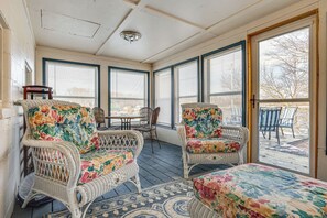Un solarium con mobiliario de mimbre, ventanas amplias y vistas al exterior.