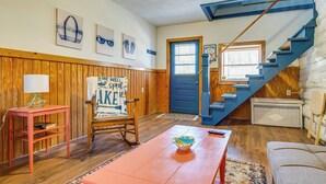 A room with a wooden floor, a blue door, a staircase, a rocking chair, a table, and a couch. - Family Home in Monticello! Water-View Retreat (Monticello)