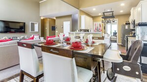 Une cuisine moderne avec des meubles blancs, une table à manger pour quatre personnes et un ventilateur de plafond.