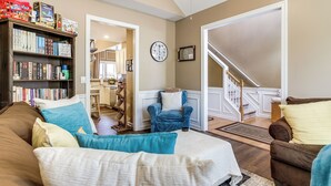 Un salon avec un canapé, un fauteuil, une bibliothèque et un escalier.