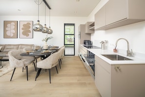 A modern kitchen with a dining area, a built-in dishwasher, and a large window.
