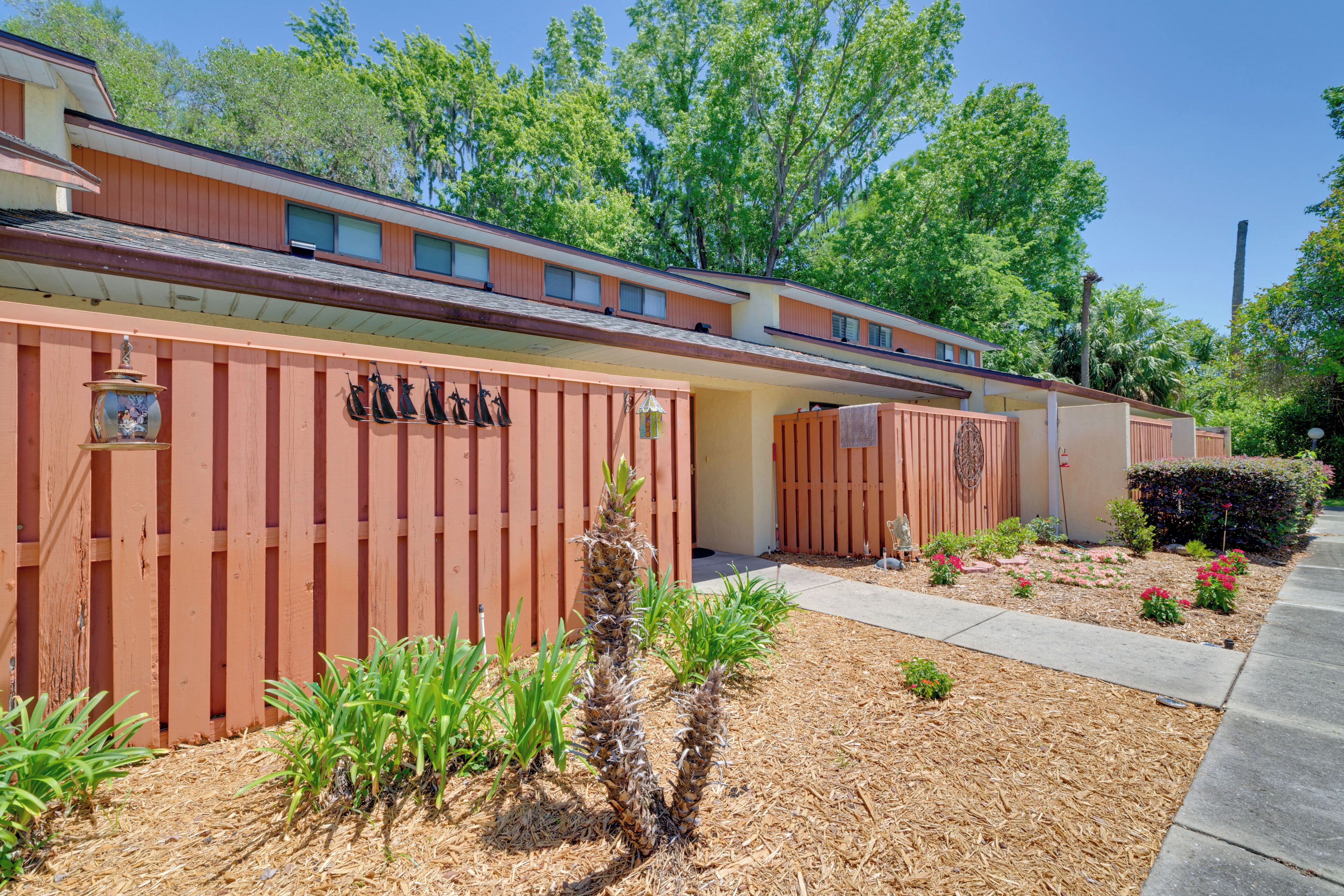 A row of cabins with a wooden fence, a small garden area with plants, and a clear sky.