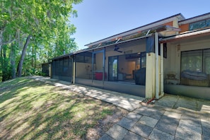 A modern house with large glass windows, a covered outdoor area, and a well-maintained lawn.