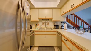 Una cocina equipada con refrigerador, gabinetes, un lavamanos y una cafetera.