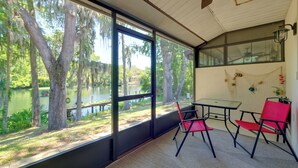 Una habitación con amplios ventanales que dan a un lago, una mesa con sillas y una pared decorada con peces.