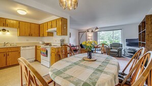 Une cuisine avec des meubles de rangement en bois, une cuisinière et un coin repas comprenant une table et des chaises.