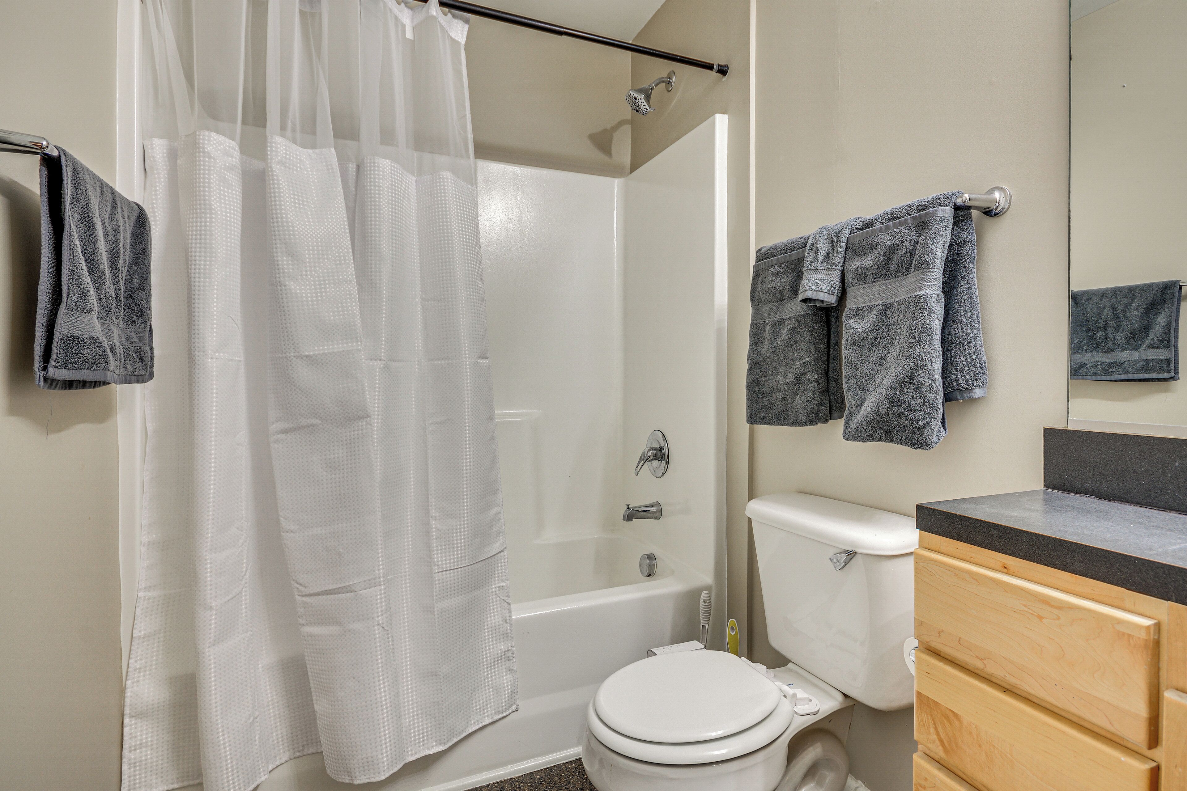 A bathroom with a bathtub, toilet, and wooden vanity.