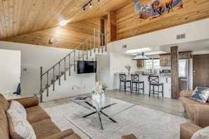 A spacious living area with a staircase, a kitchen, and a dining area.
