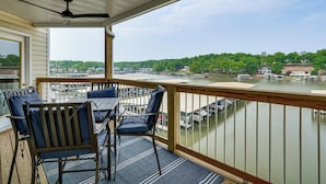 Een balkon met een tafel en stoelen, met uitzicht op een waterpartij met boten en huizen op de achtergrond.